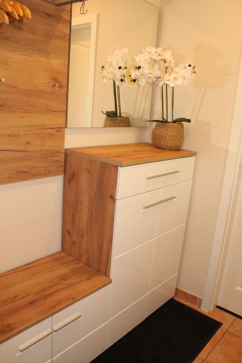 Eingangsbereich mit Holzbank, Schuhschrank und Orchidee