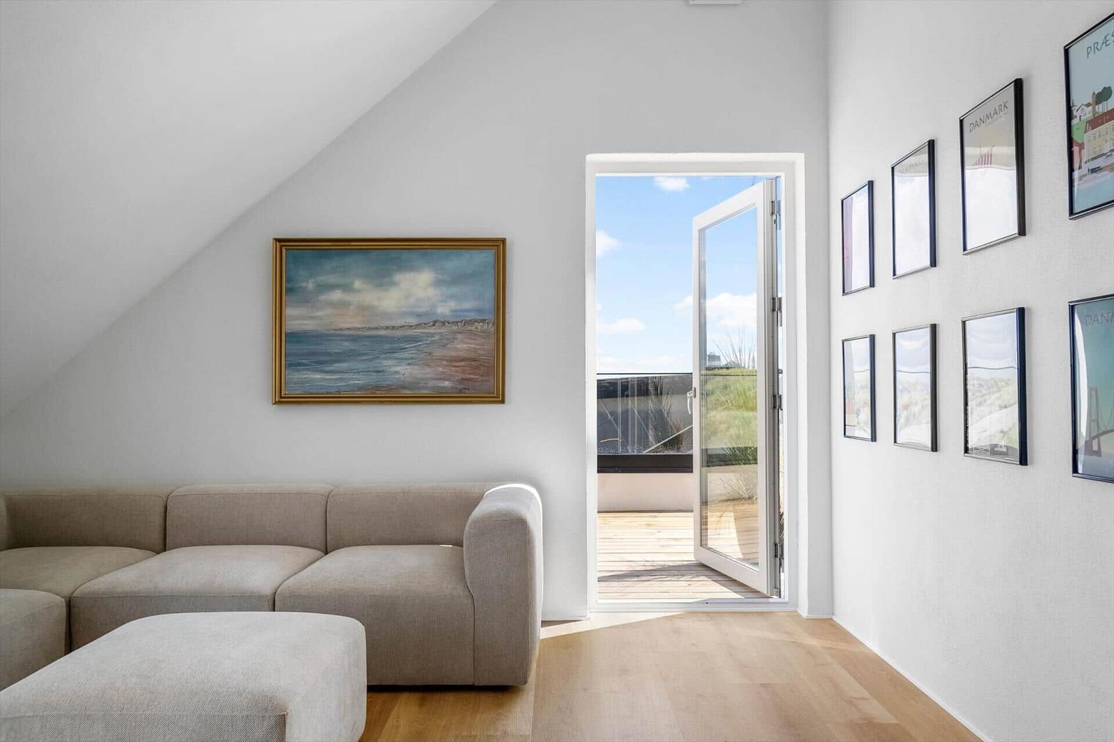 Wohnzimmer mit Sofa, Tür zum Balkon und Wandbildern.