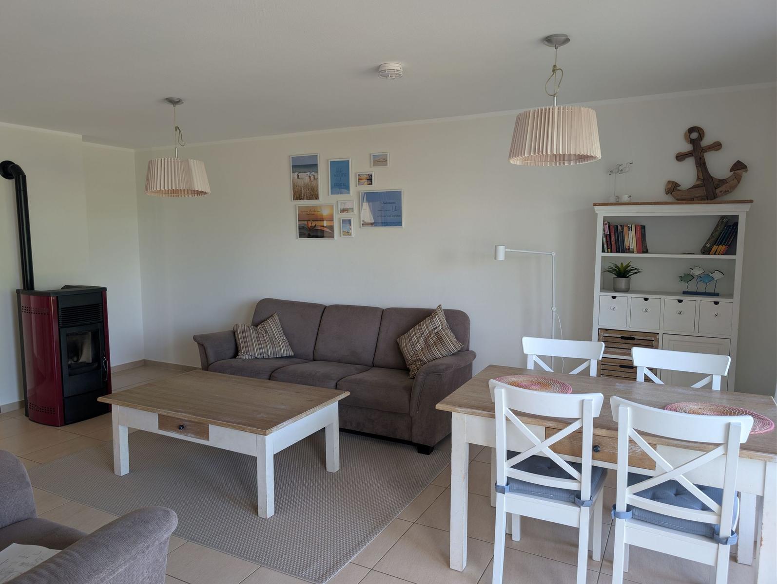 Wohn- und Essbereich mit Sofa, Tisch, Stühlen und Kamin.