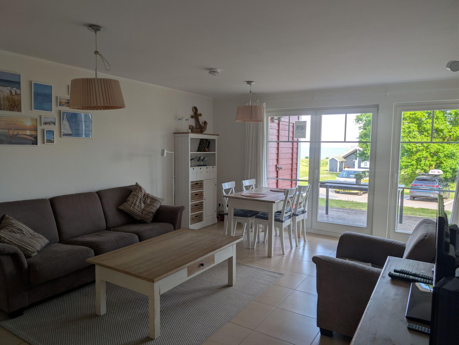 Wohn- und Essbereich mit Sofa, Tisch und Blick auf Balkon und Garten.