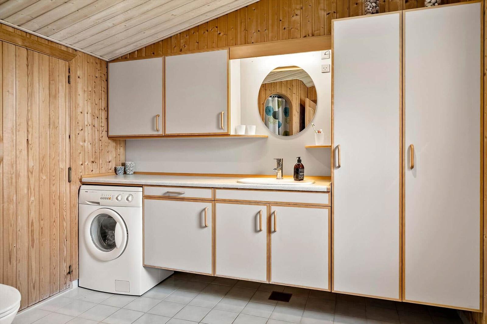 Waschraum mit Waschmaschine, Spüle und Spiegelschrank.