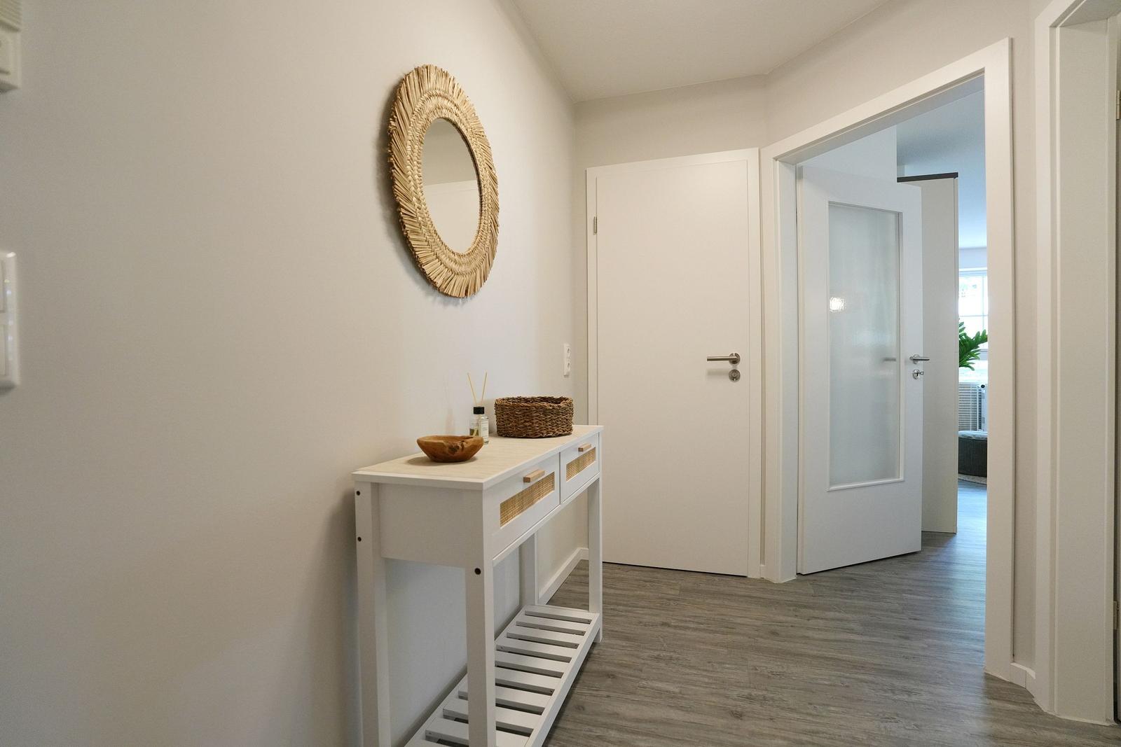 Eingangsbereich mit Schuhschrank, Wandspiegel und Tür zu Wohnraum.