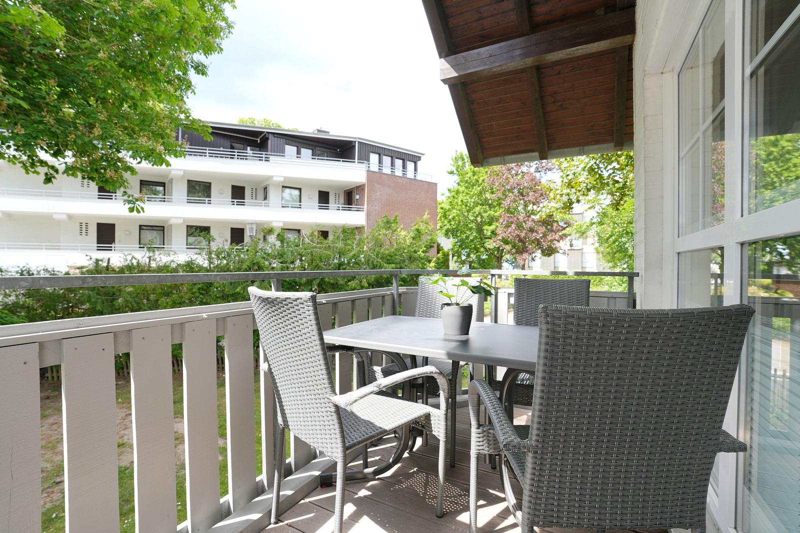 Terrasse mit Tisch und Stühlen, Blick auf Wohnhaus und Bäume