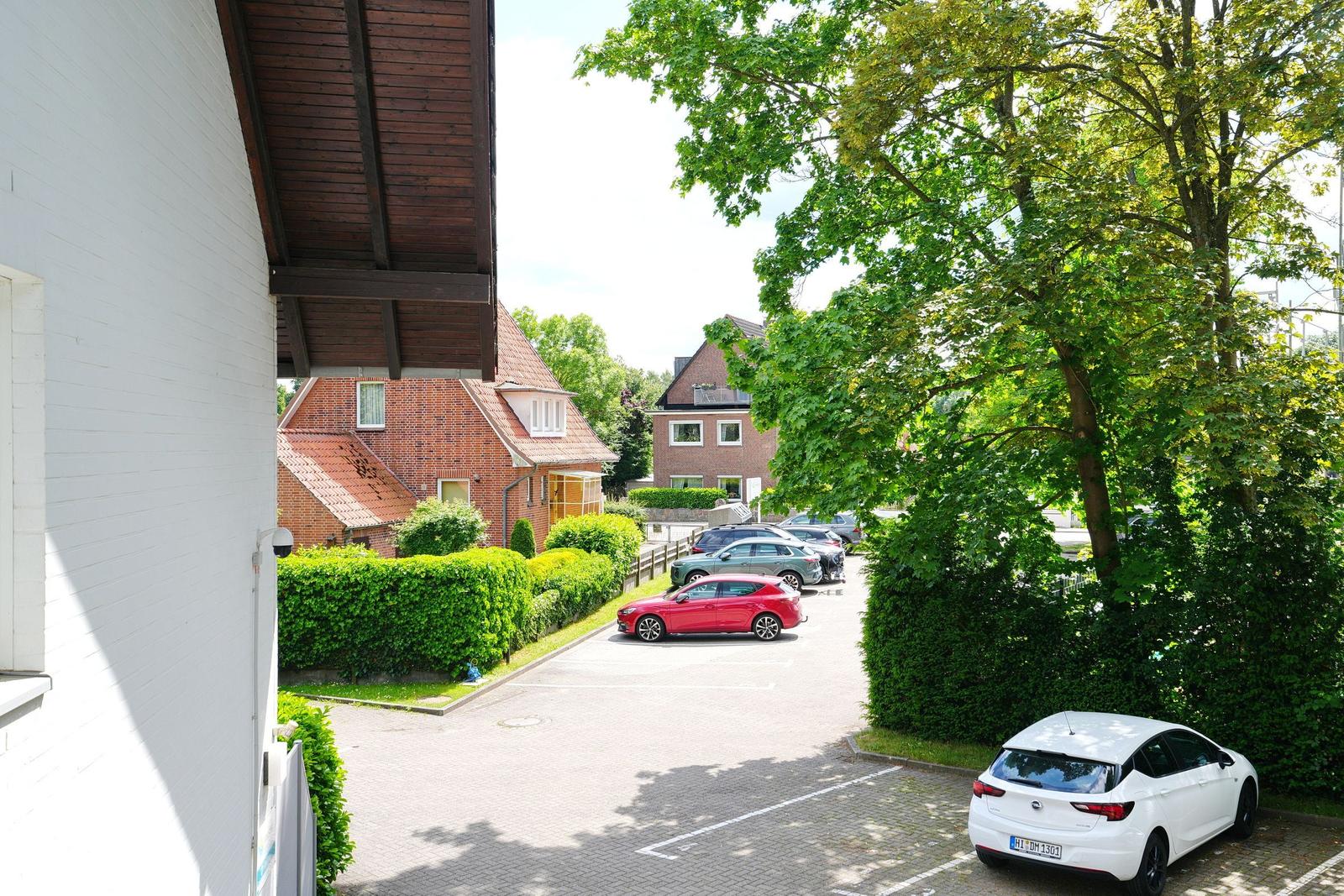 Parkplatz mit mehreren Autos und grünen Bäumen im Hintergrund.
