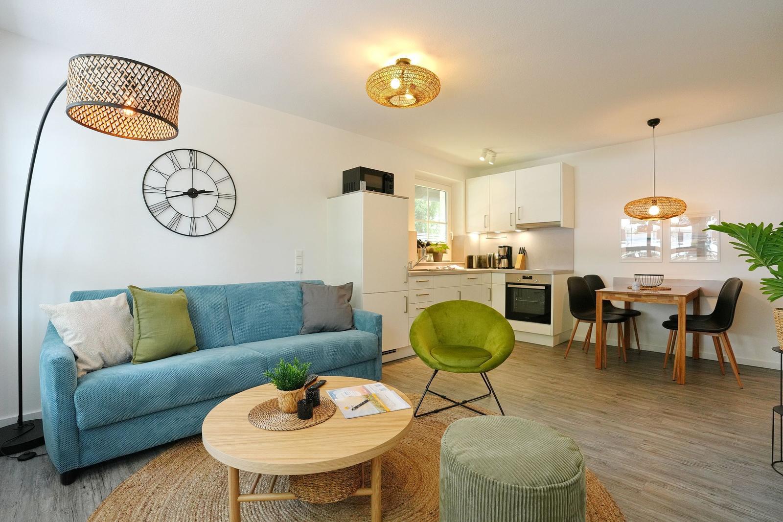Wohn- und Essbereich mit Sofa, Essplatz und Küchenzeile.