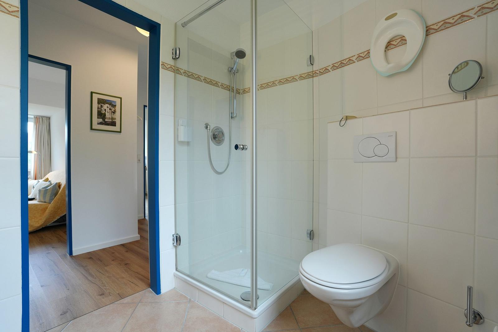 Badezimmer mit Dusche, Toilette und Blick in Schlafzimmer.
