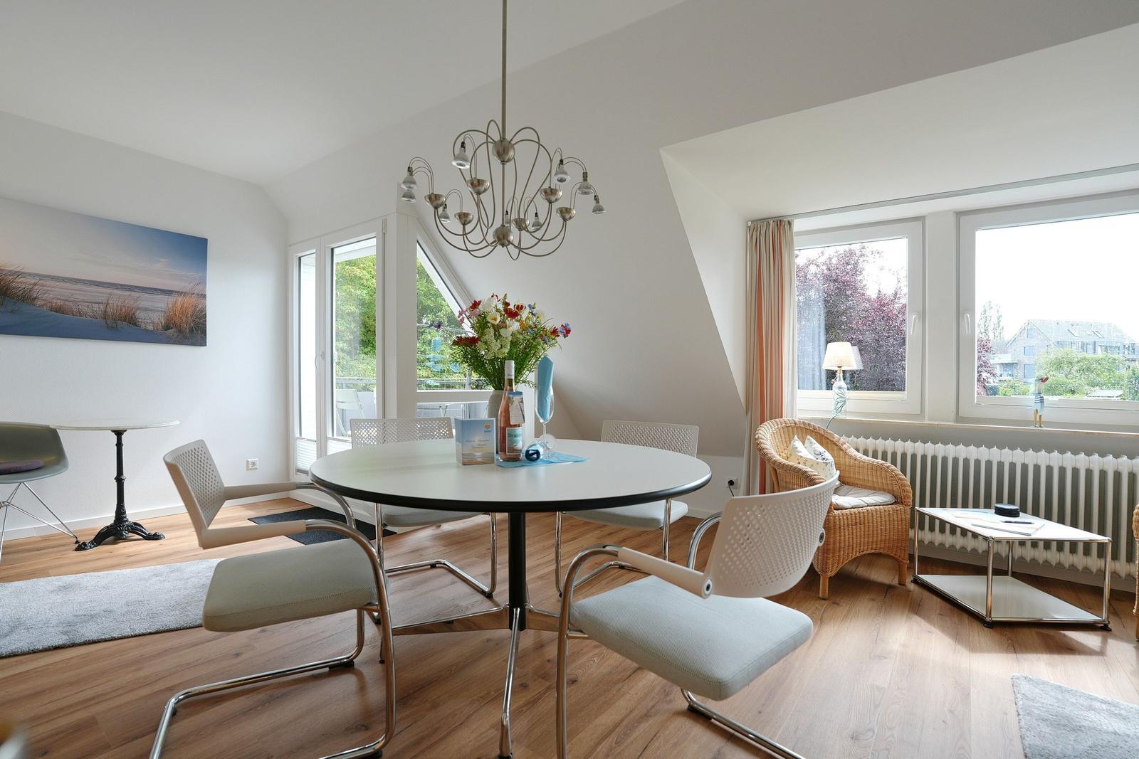 Rundtisch mit Stühlen, Sessel und Fenster im Wohnbereich.