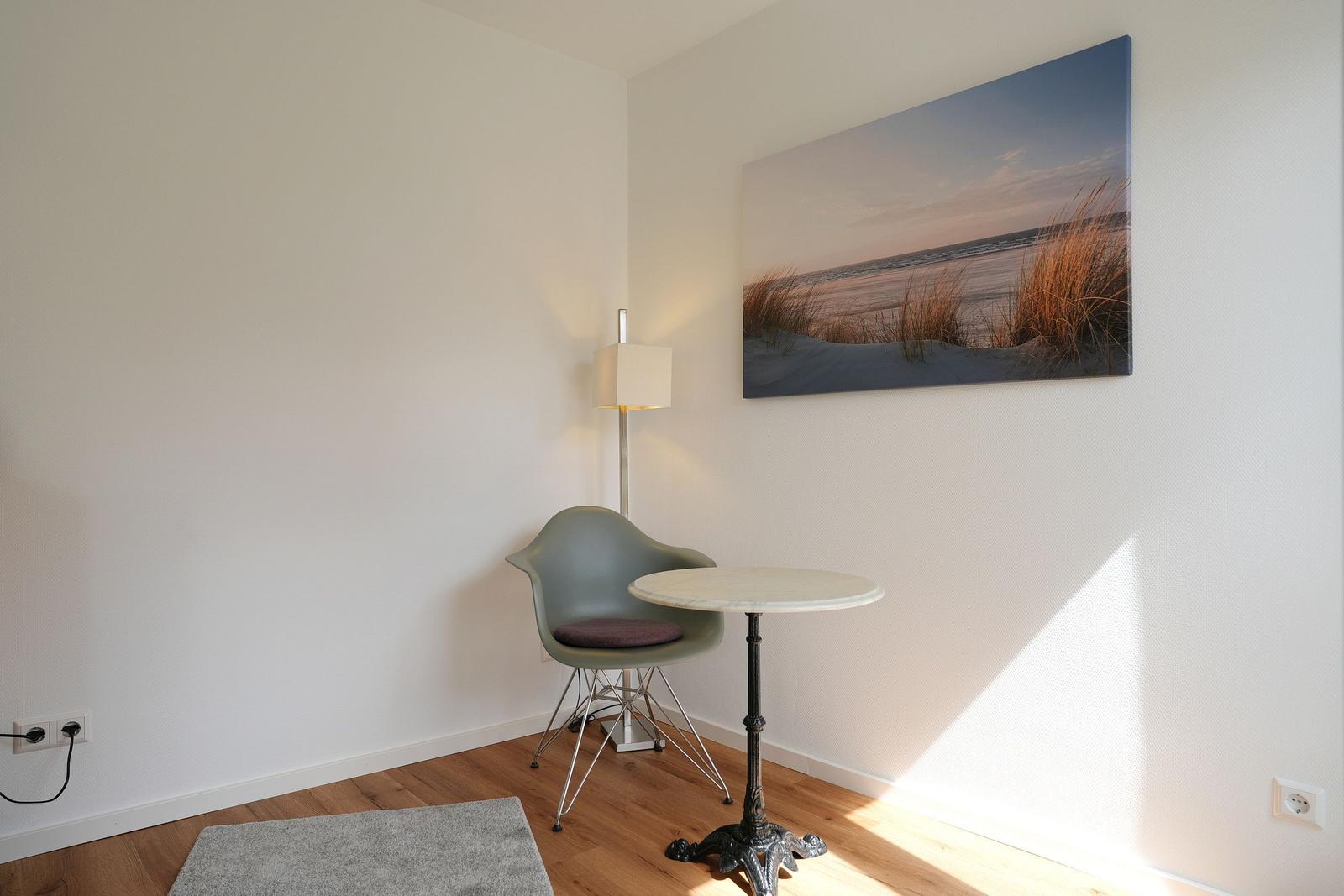 Eckzimmer mit Stuhl, Tisch und Wandbild von Strand