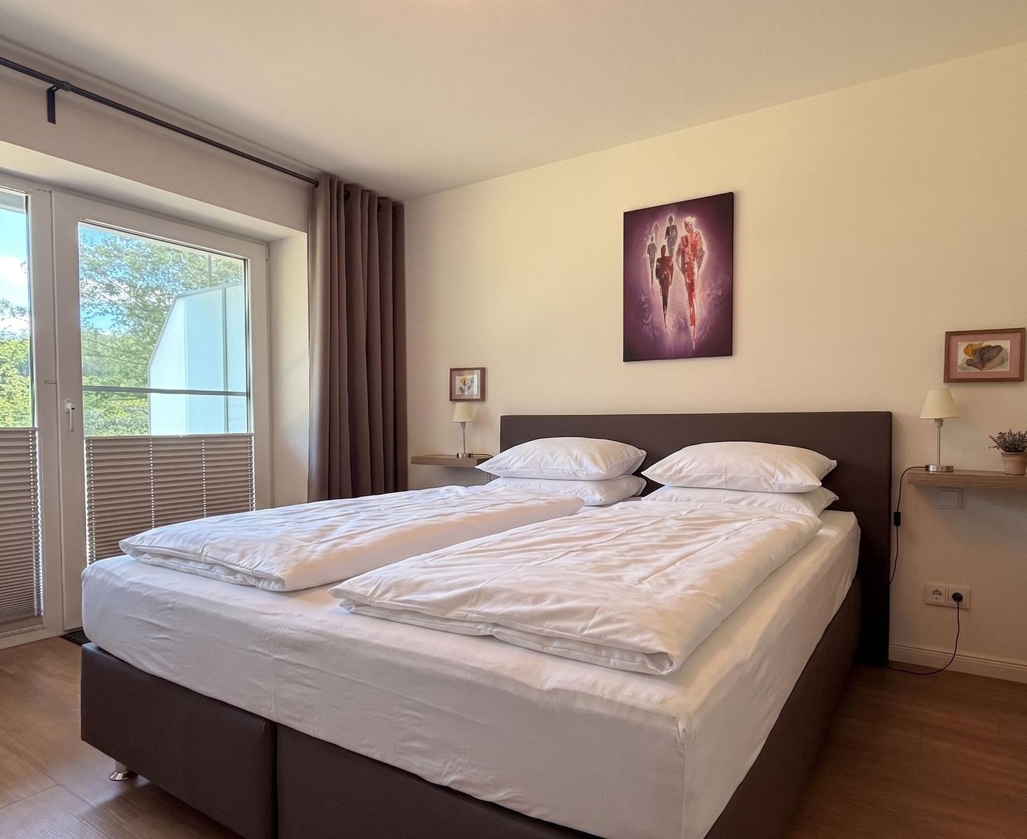 Schlafzimmer mit Doppelbett, Fenster und Wandbild.