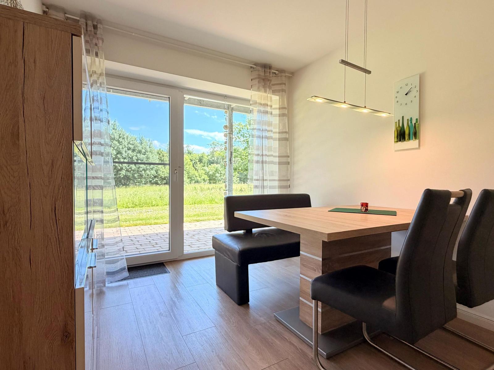 Esszimmer mit Tisch, Stühlen und Blick auf grünen Garten.