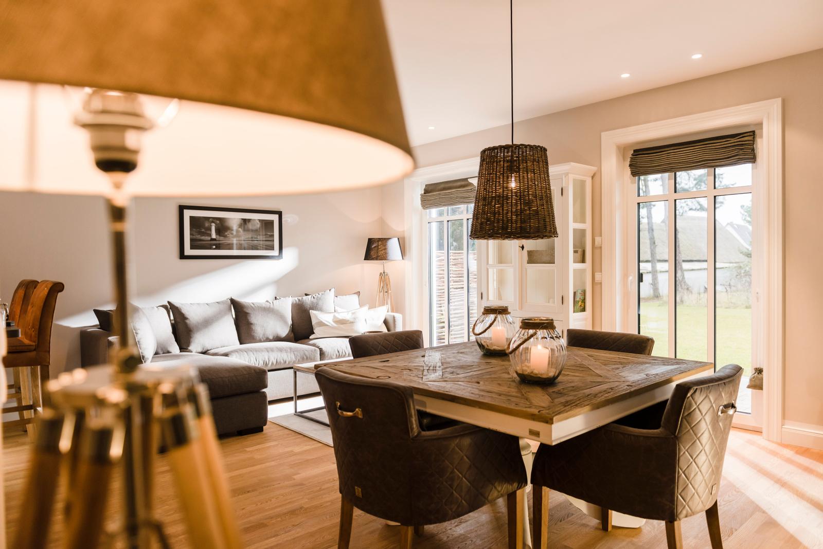 Esszimmer mit Holztisch und Stühlen, Wohnbereich mit Sofa und Fenster zur Außenterrasse.