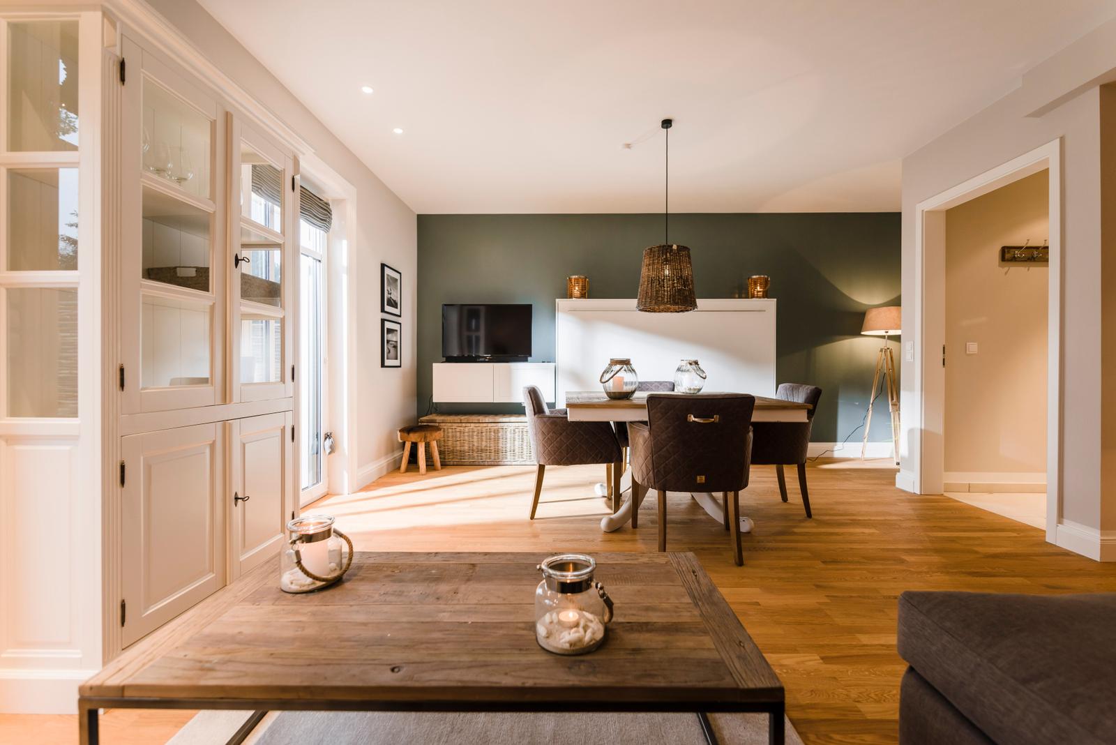 Wohn- und Essbereich mit Holzboden, Esstisch, TV und Schrank