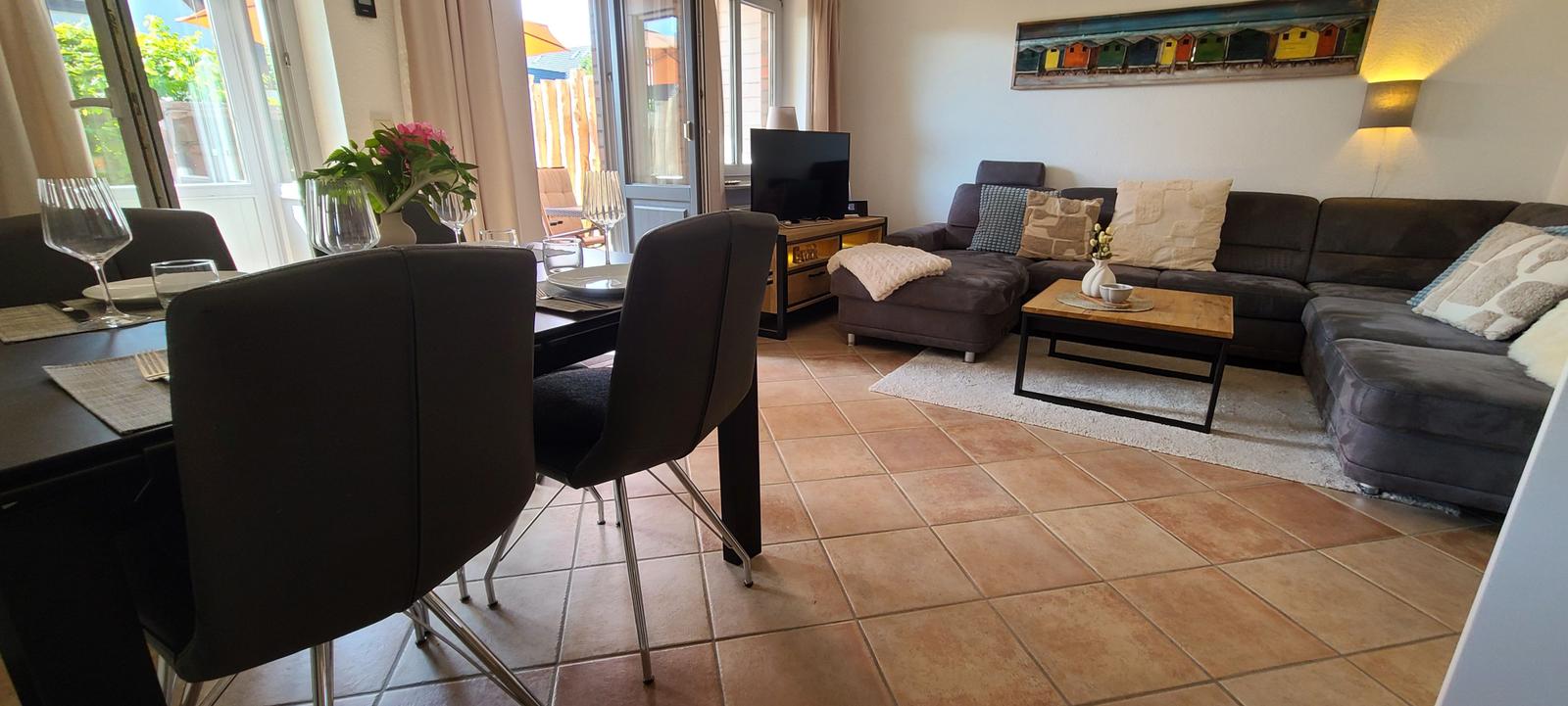 Wohn- und Essbereich mit Sofa, Esstisch und Terrassentür.