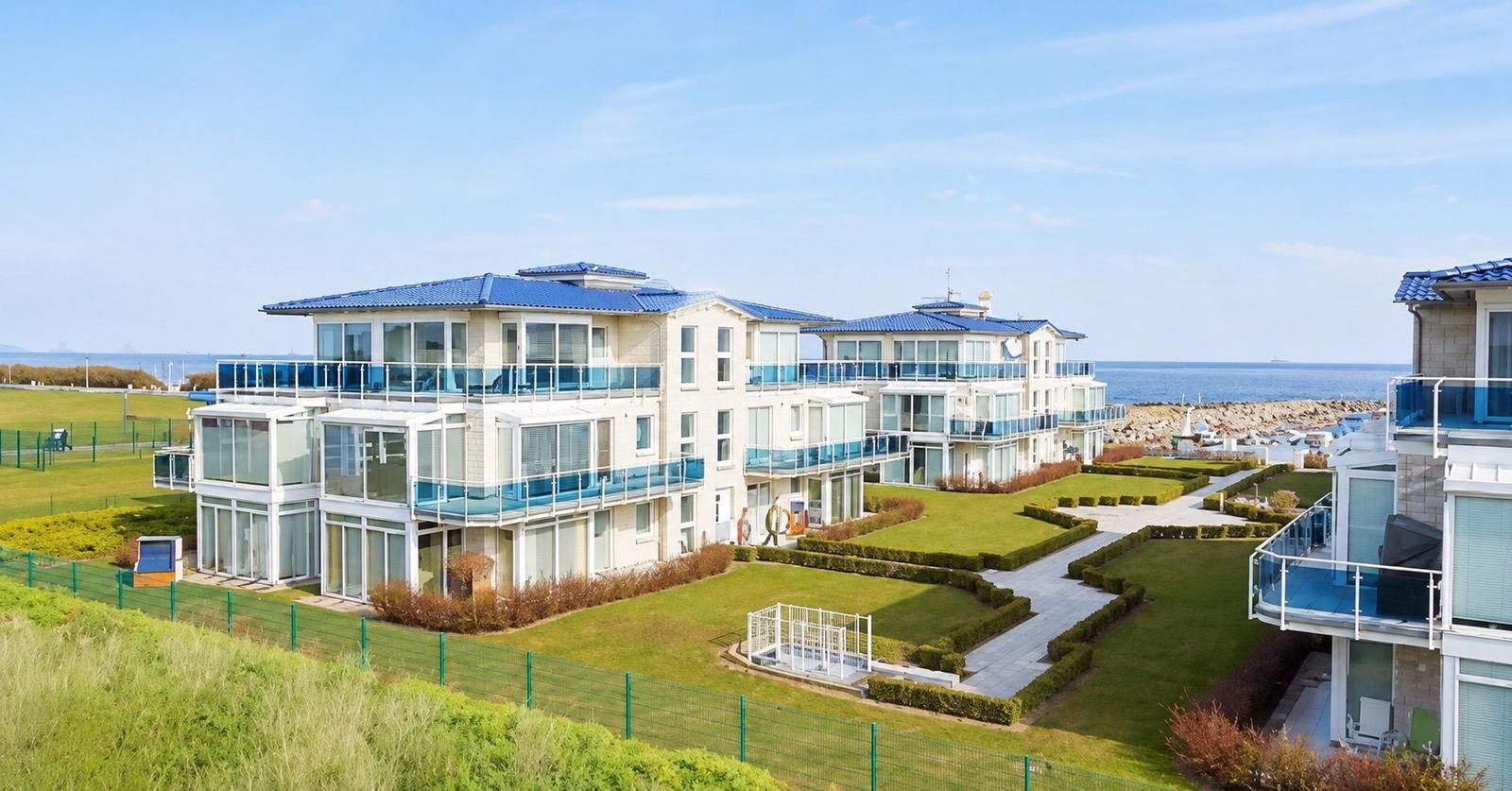 Moderne Wohnanlage mit Balkonen und Gartenbereich direkt am Meer.
