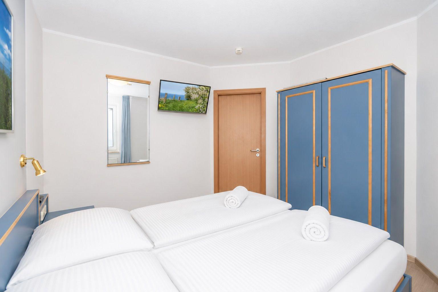 Schlafzimmer mit Doppelbett, blauem Schrank und Wandbild