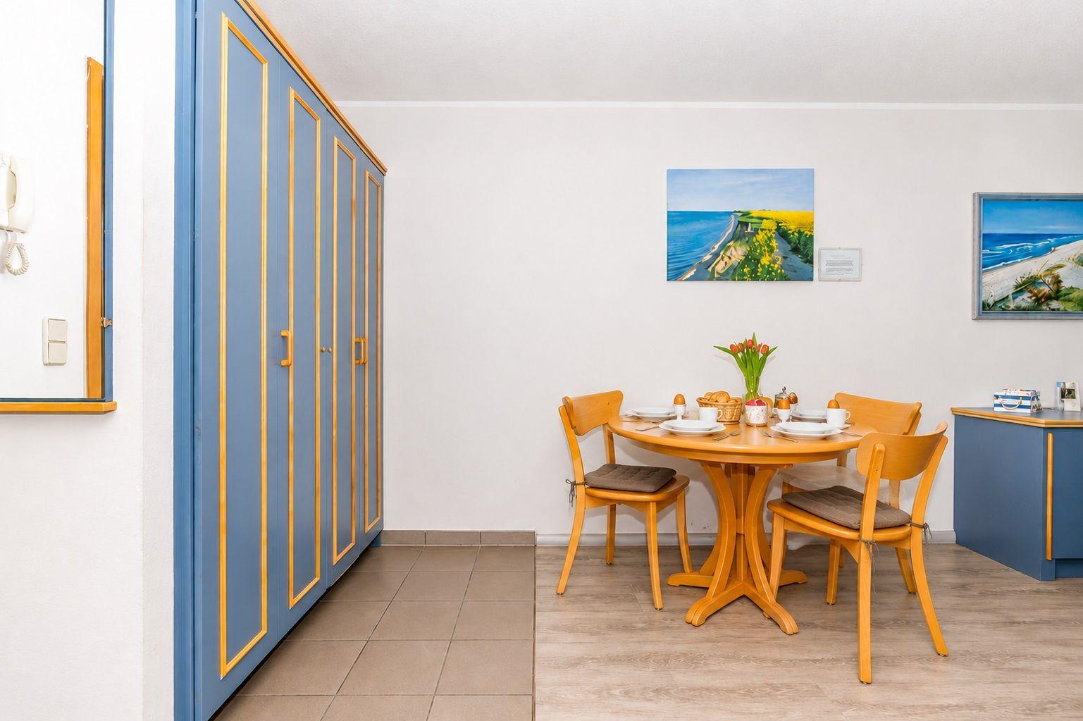 Esszimmer mit Holztisch, vier Stühlen und blauen Schränken an der Wand.