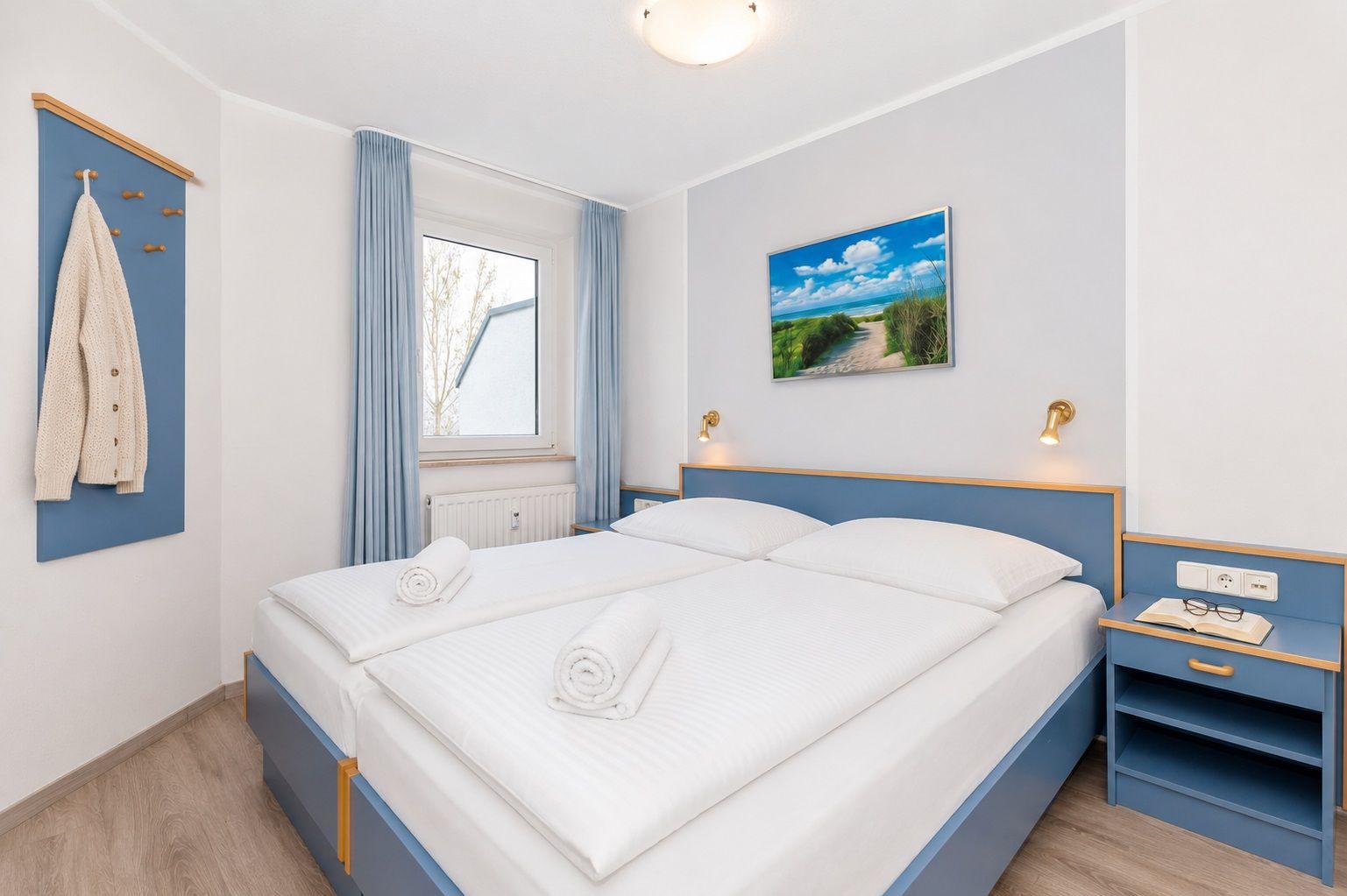 Schlafzimmer mit Doppelbett, blauen Möbeln und Fenster mit Blick nach draußen.