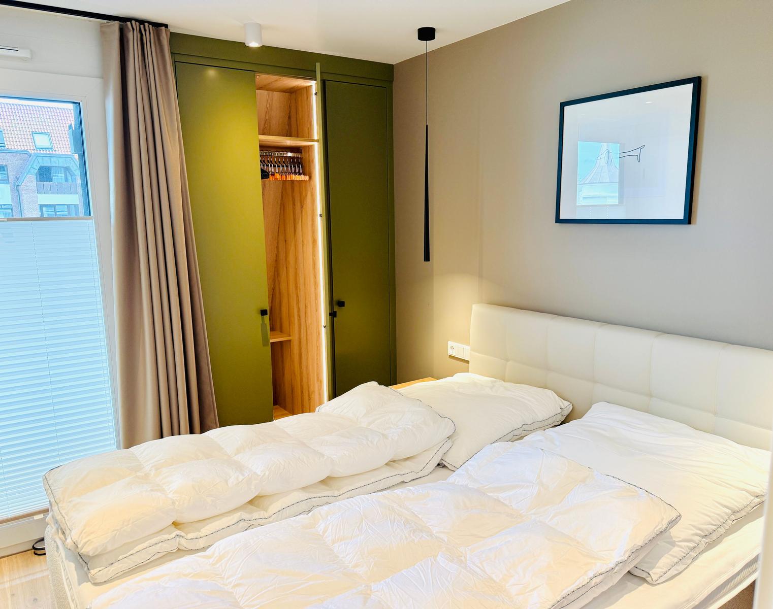 Schlafzimmer mit Bett, Kleiderschrank und Fenster