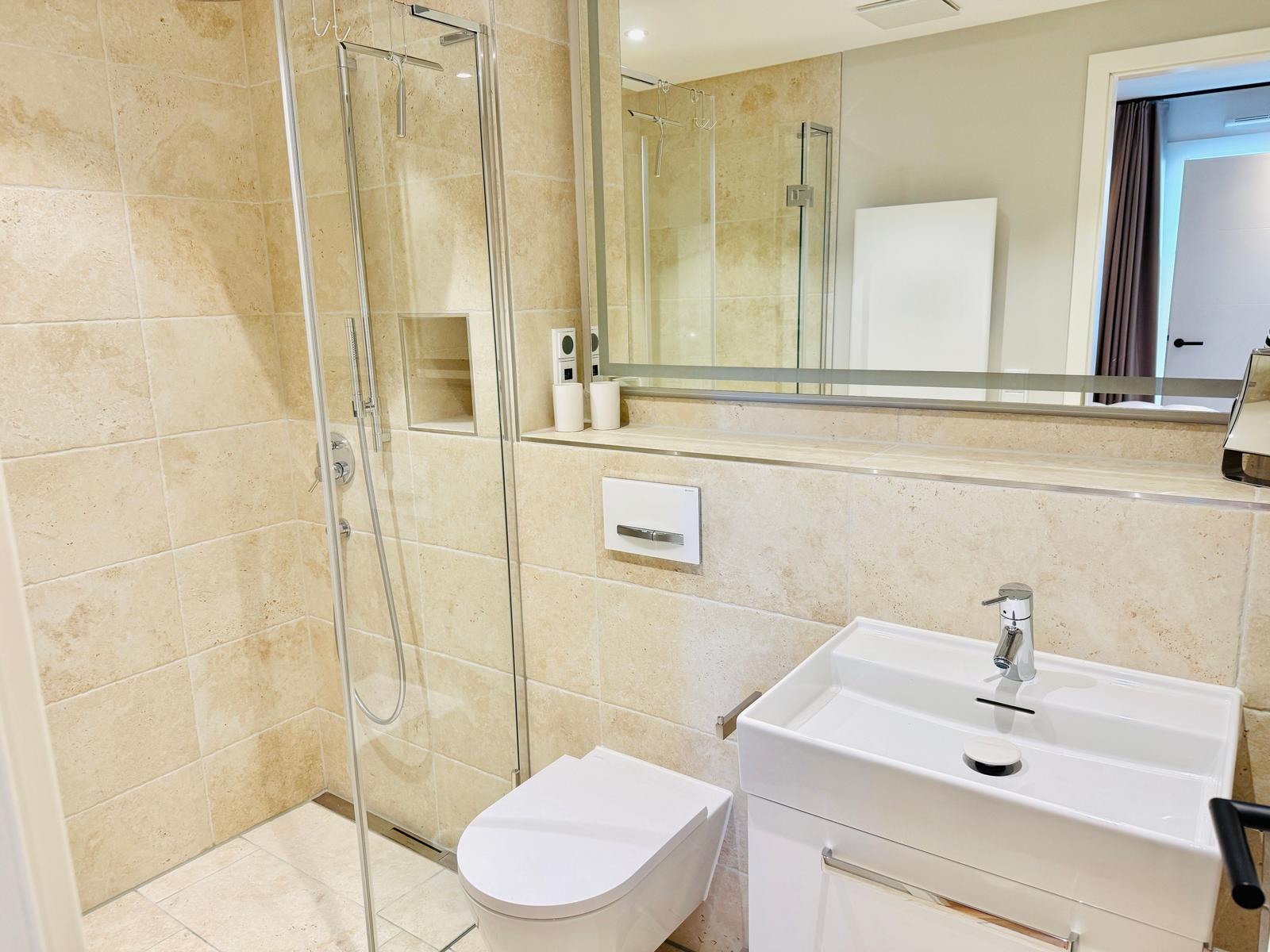 Badezimmer mit Dusche, Toilette und Waschbecken.