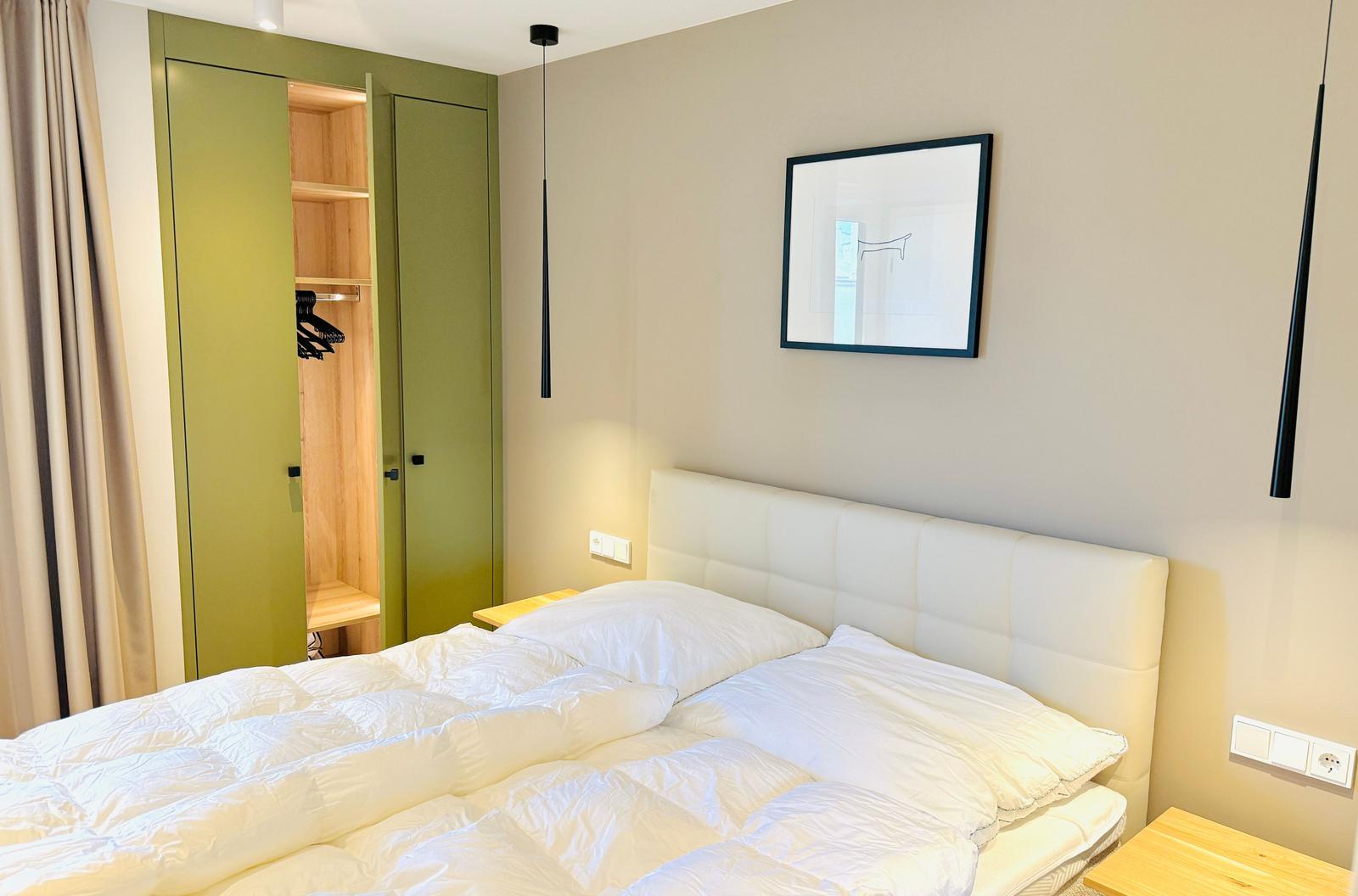Schlafzimmer mit Bett, Kleiderschrank und Wandbild.