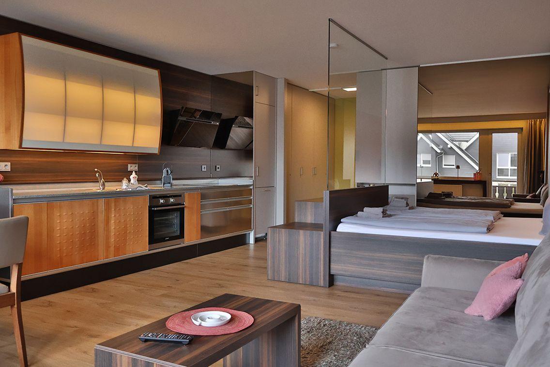 Moderne Einzimmerwohnung mit Küche, Schlafbereich und Sitzgelegenheit.