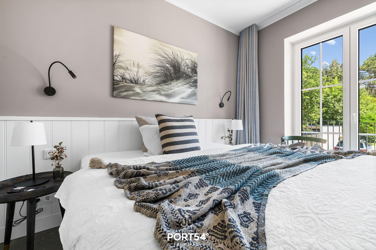 Schlafzimmer mit Bett, Wandbild und Fenster zur Terrasse