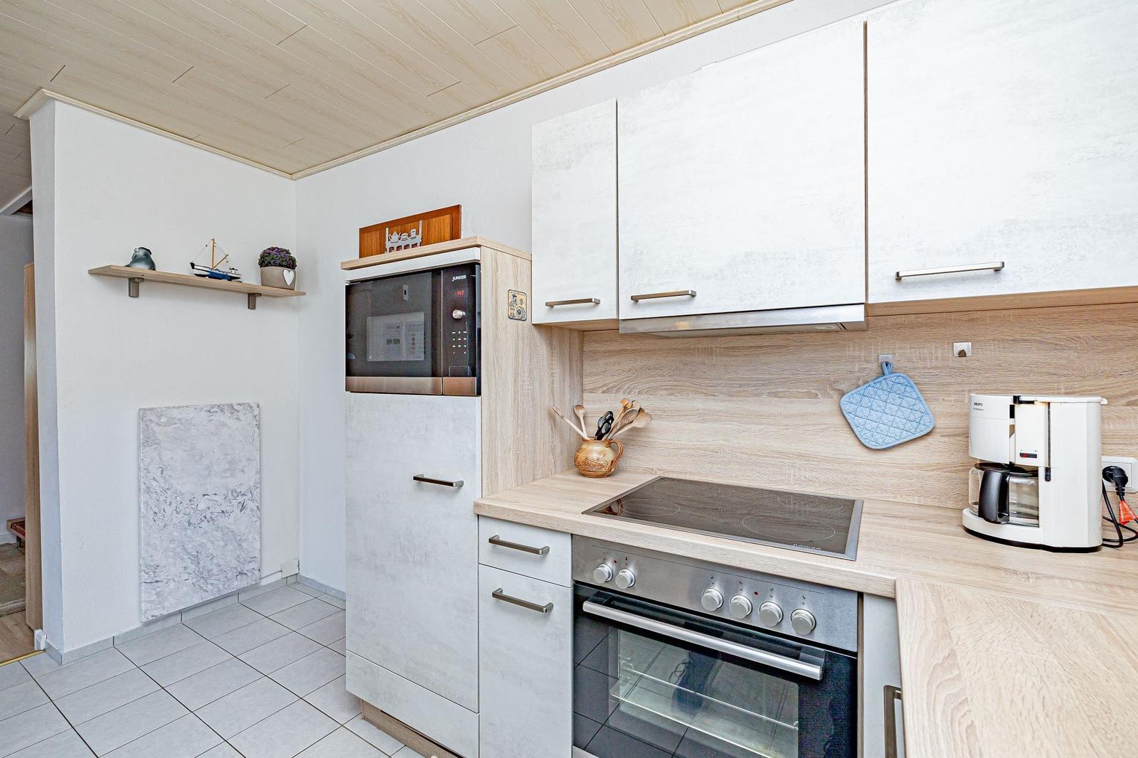 Küche mit Dunstabzug, Herd, Kühlschrank und Arbeitsfläche.