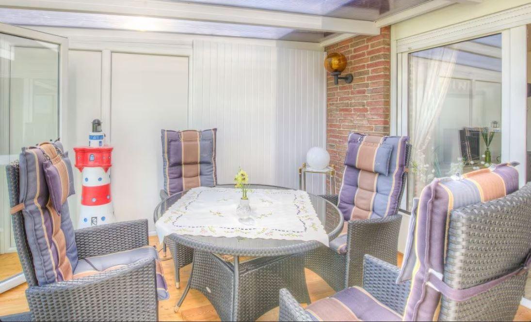 Terrasse mit runden Tisch und Stühlen, rotem Leuchtturm und Backsteinwand.