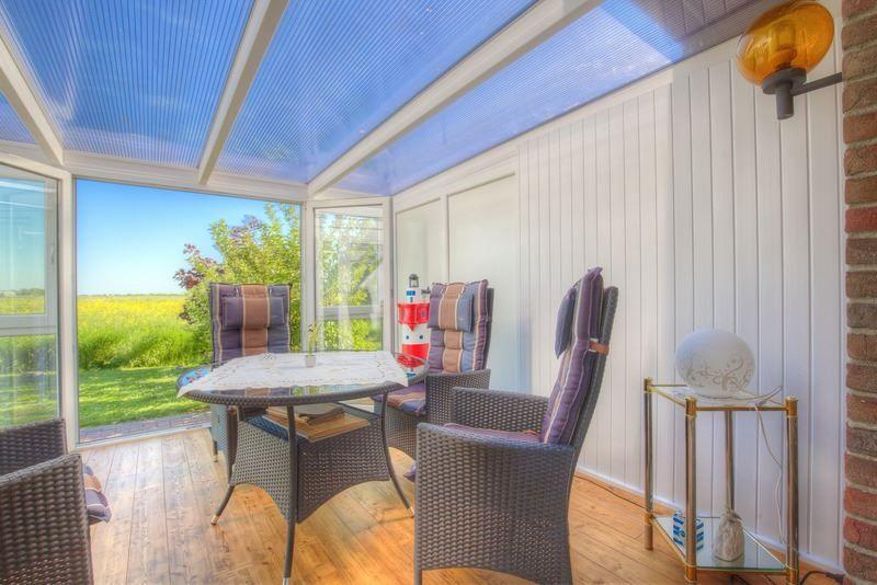 Terrasse mit Sitzgruppe und Blick auf grünes Feld.