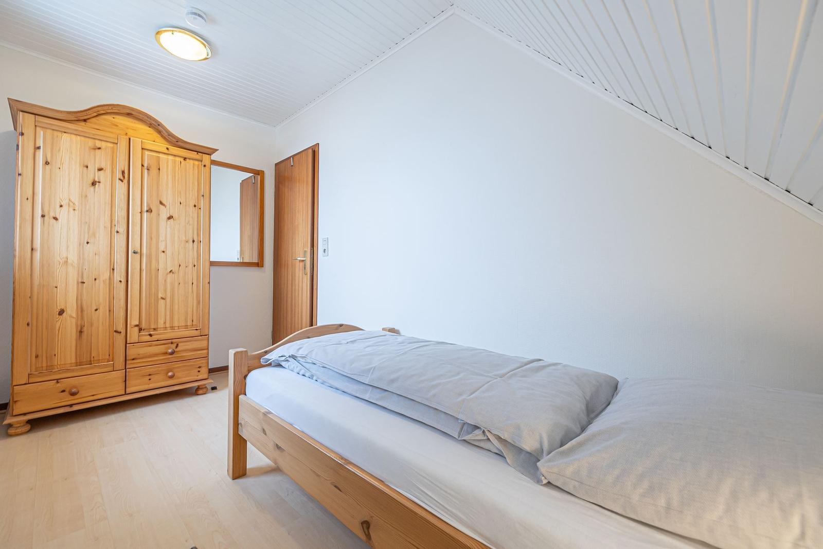 Ein Schlafzimmer mit einem Bett, einem Kleiderschrank und einer Tür.