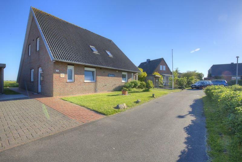 Ein zweistöckiges Haus mit Schieferdach und Vorgarten. Straße mit gepflastertem Weg.