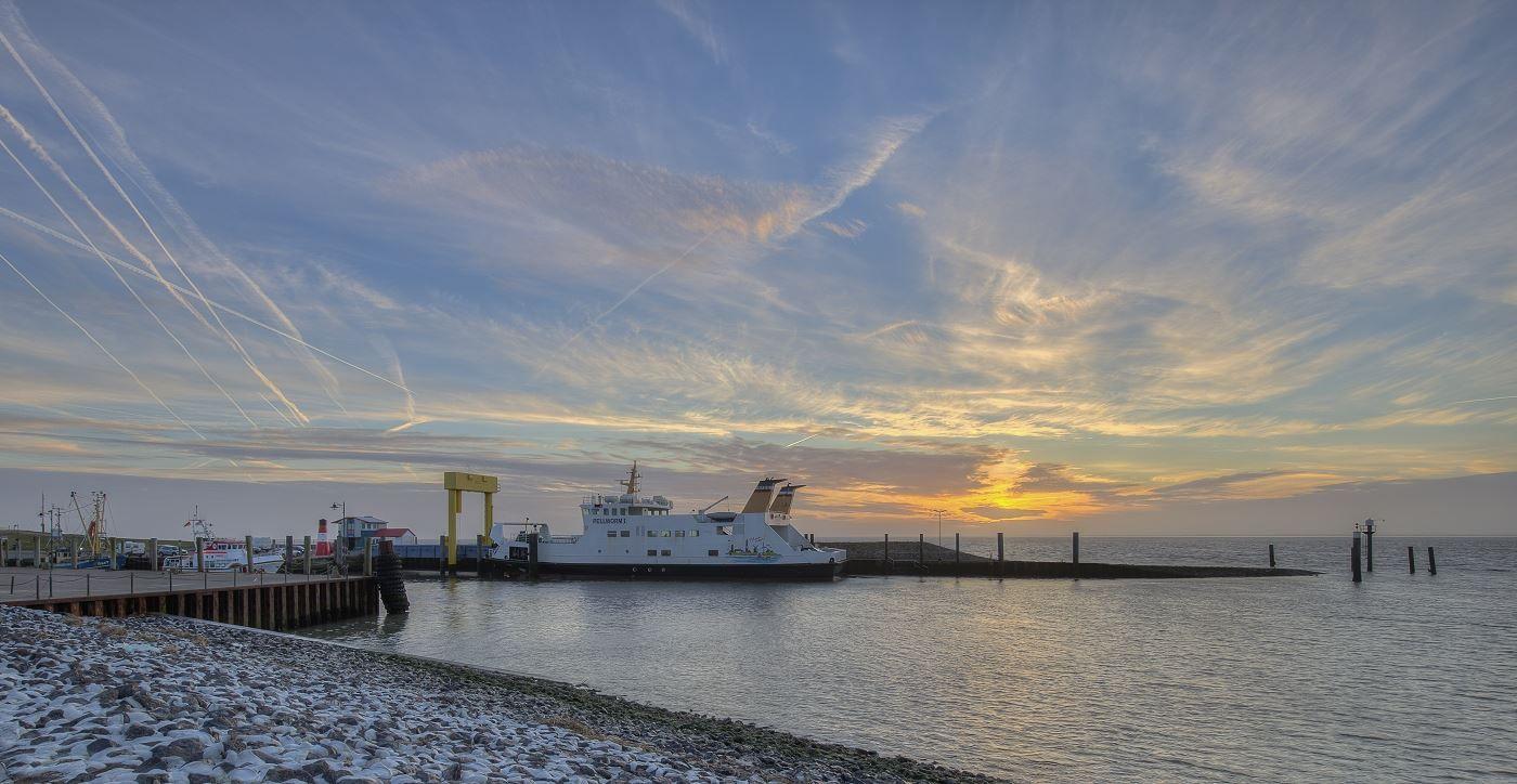 Fähranleger mit weißem Schiff bei Sonnenuntergang am Hafen.