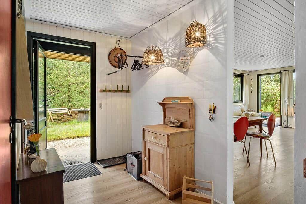 Eingangsbereich mit Holzschrank, Wandleuchten und Blick auf Garten.