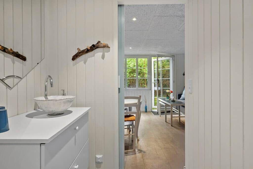 Badezimmer mit Waschbecken und Blick in Wohnbereich mit Fenster