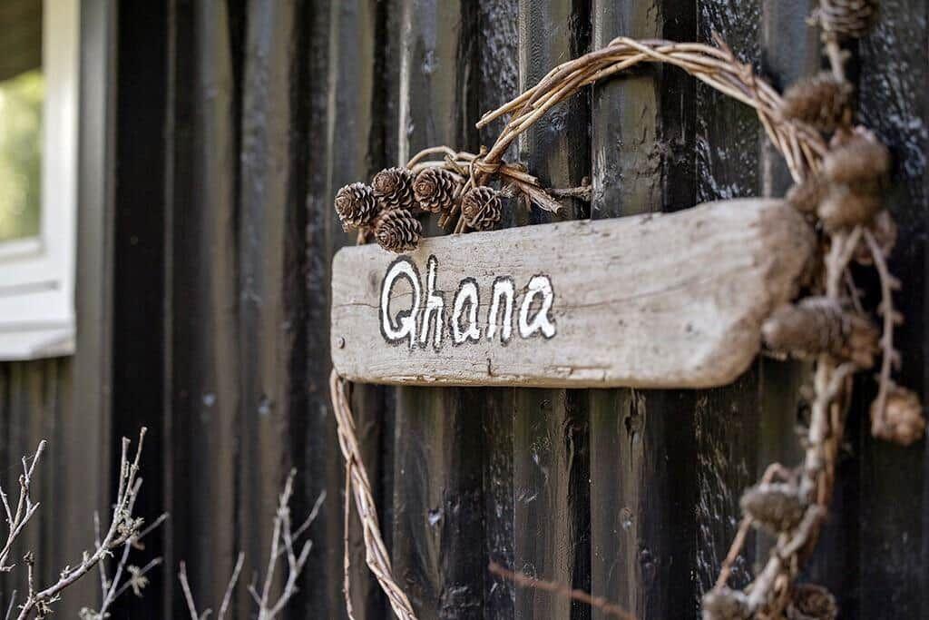 Holzschild mit der Aufschrift Ghana an einer dunklen Holzwand.