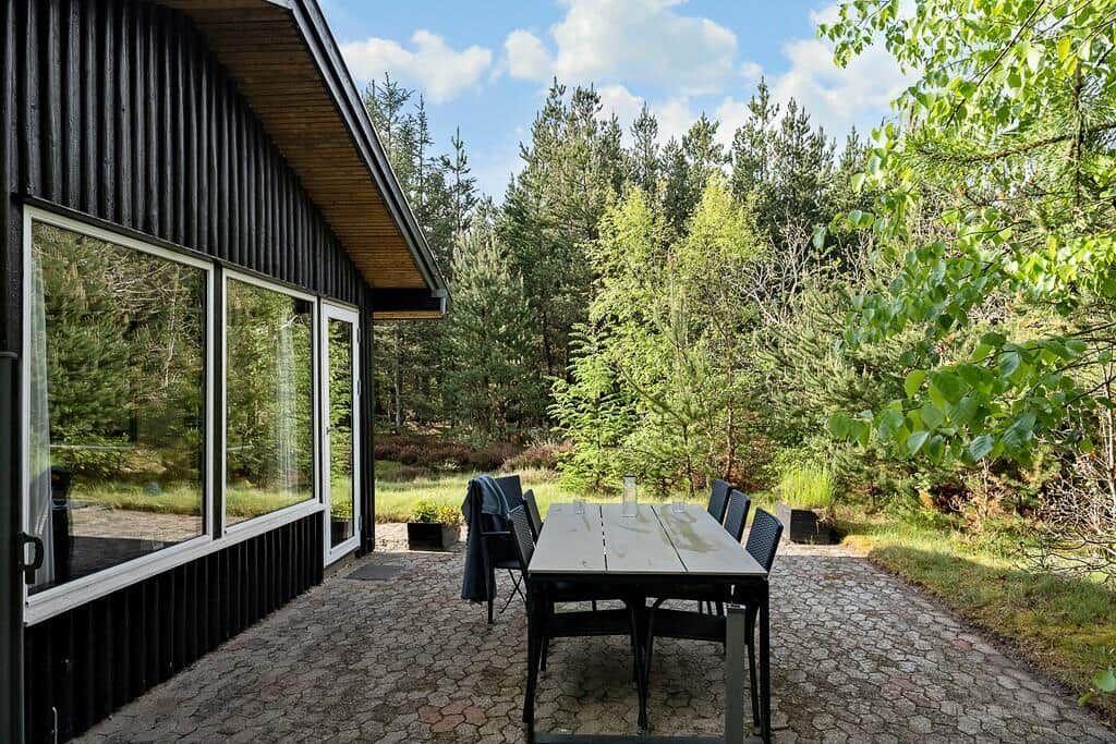 Terrasse mit Tisch und Stühlen neben einem Haus im Wald.