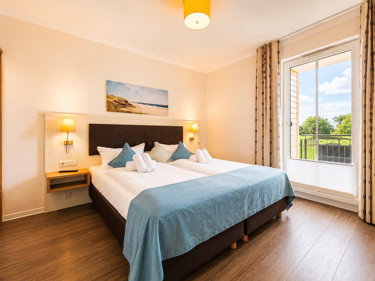 Schlafzimmer mit Doppelbett, Schlafcouch und Balkonansicht.