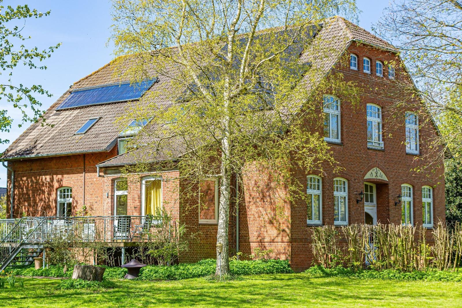 Rotes Backsteingebäude mit Solaranlage, Balkon und Garten