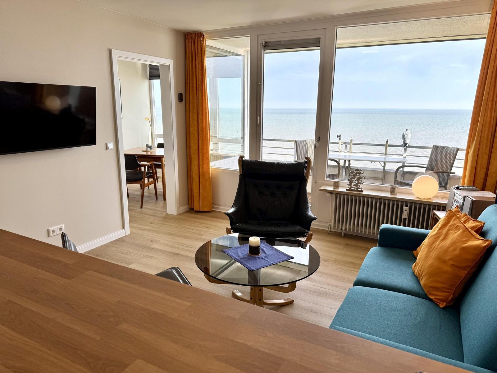 Living room with sofa, armchair, and sea view.