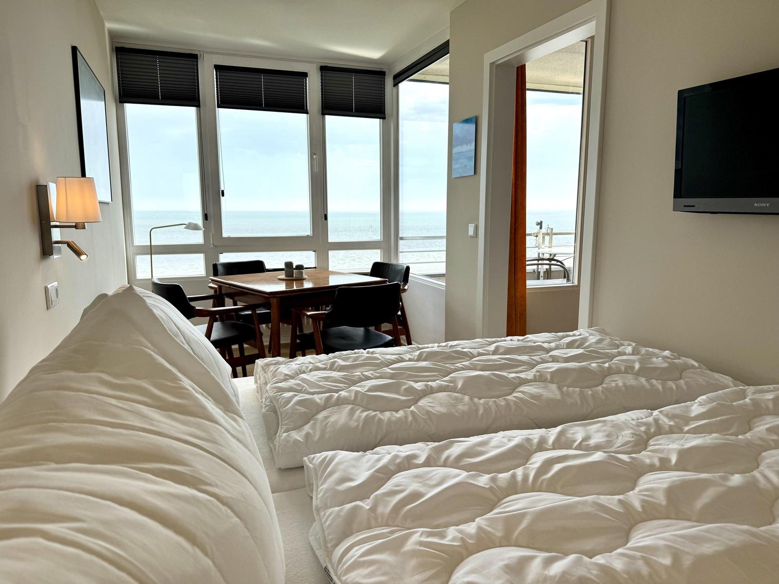 Bedroom with sea view and dining area with table and chairs.