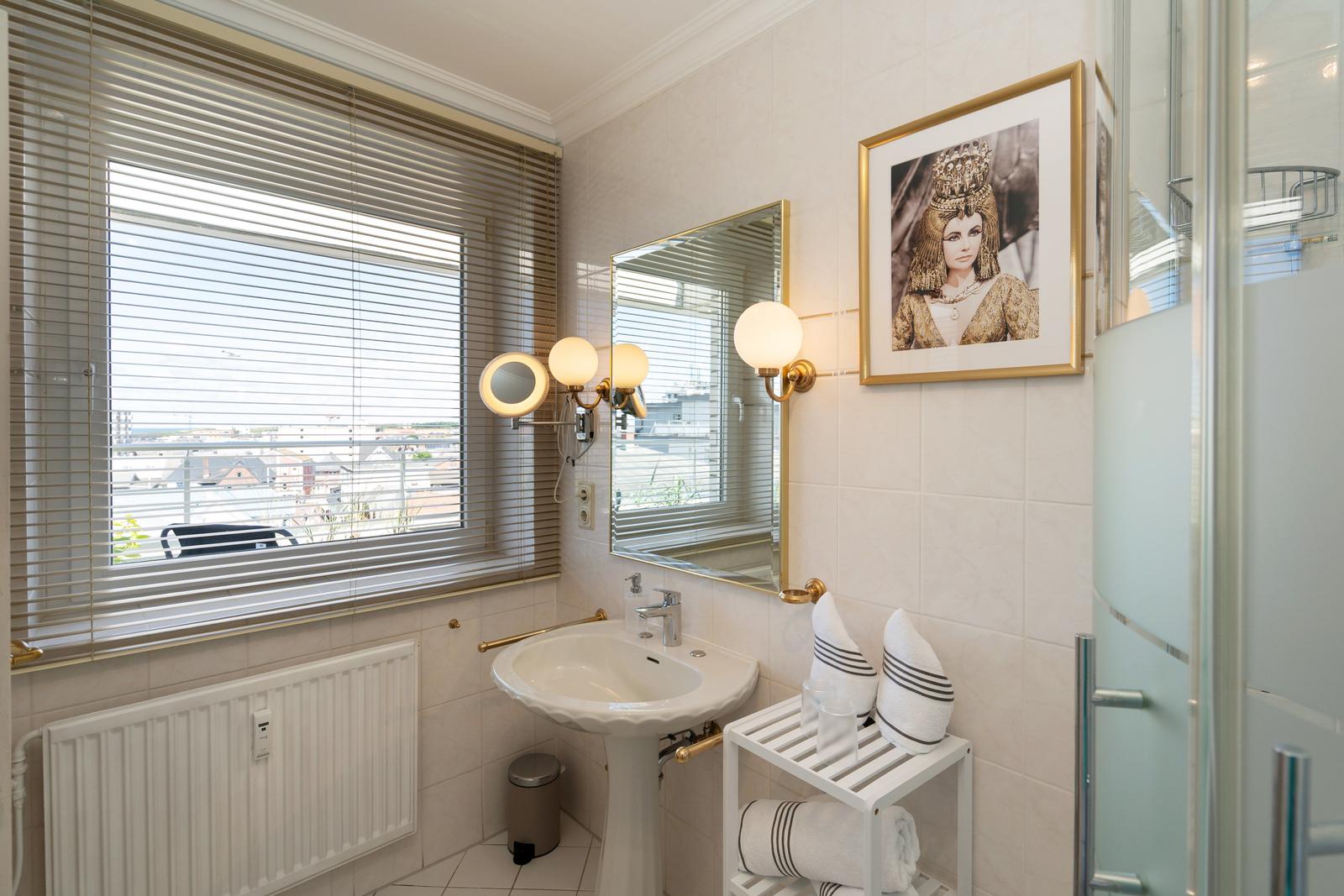 Badezimmer mit Waschbecken, Spiegel, Dusche und Fenster mit Blick.