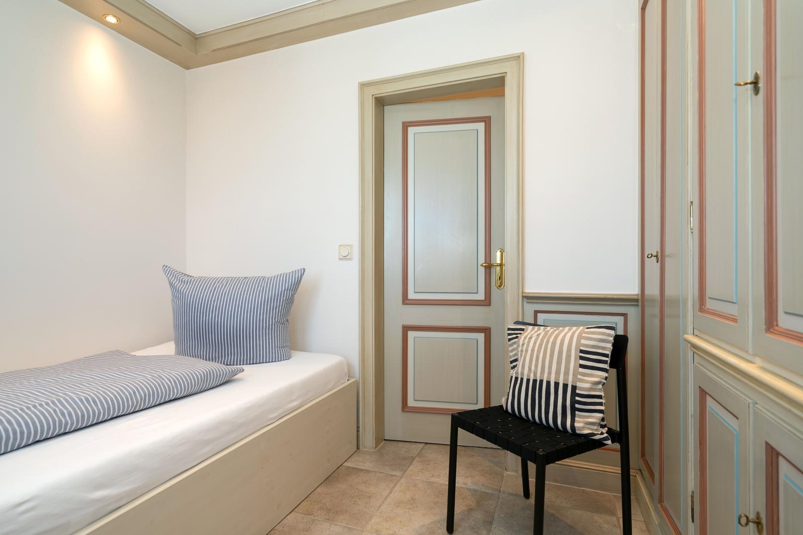 Schlafzimmer mit Bett, Stuhl und Schrank. Tür und Wandverkleidung mit Farbverlauf.