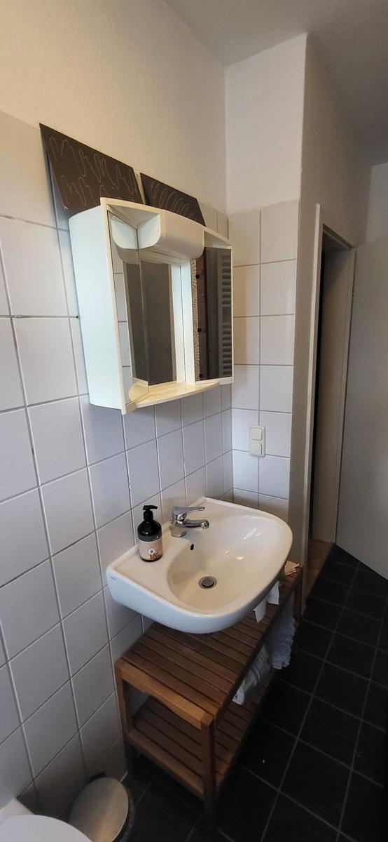Badezimmer mit Waschbecken, Spiegelschrank und Holzunterschrank.