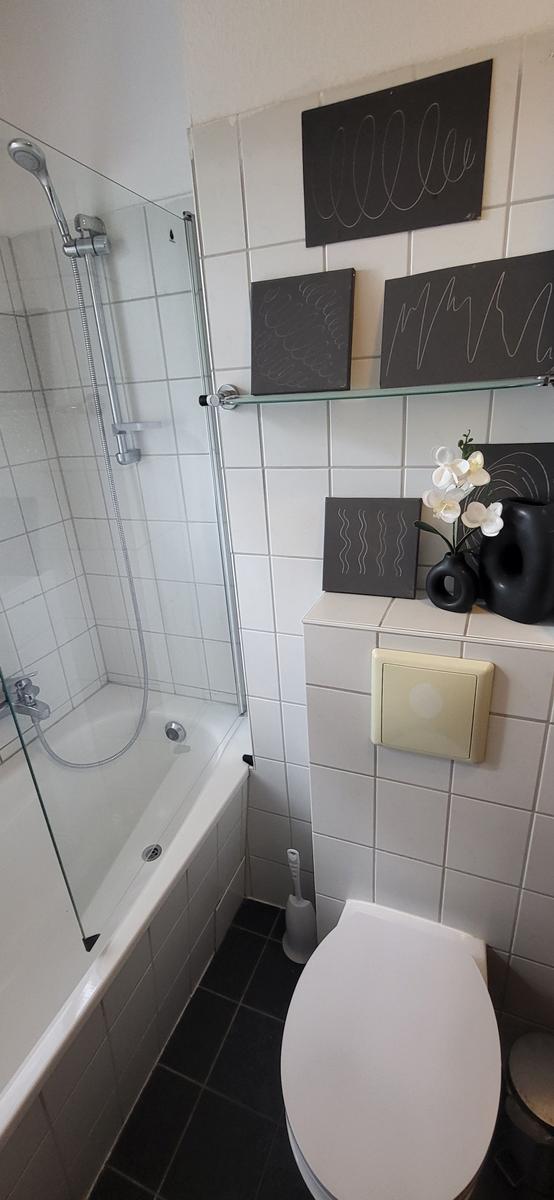 Badezimmer mit Dusche, Toilette und Wanddekoration.