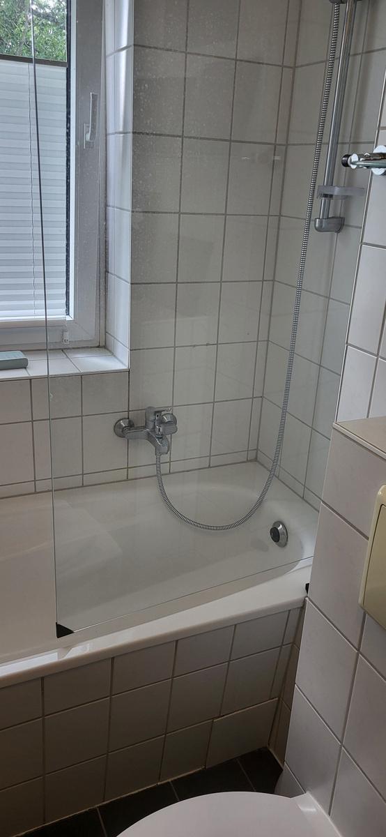 Bad mit Badewanne, Duschbrause und Fenster mit Jalousie