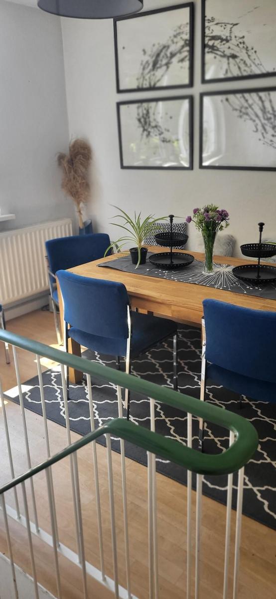 Essbereich mit Holztisch, blauen Stühlen und dekorativen Bildern an der Wand.