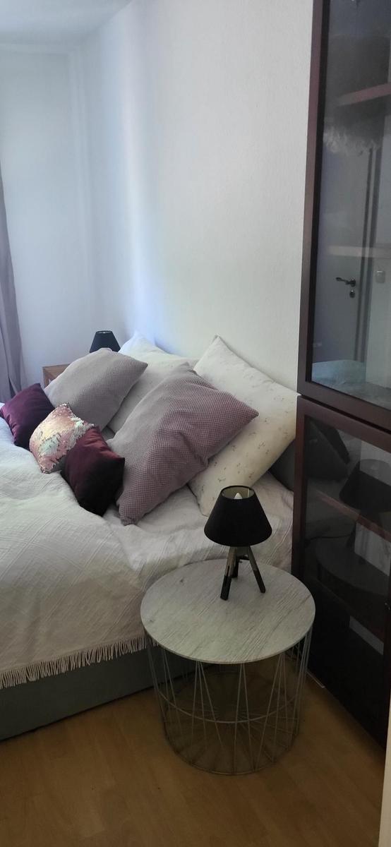 Schlafzimmer mit Bett, Kissen, Nachttisch und Schrank.