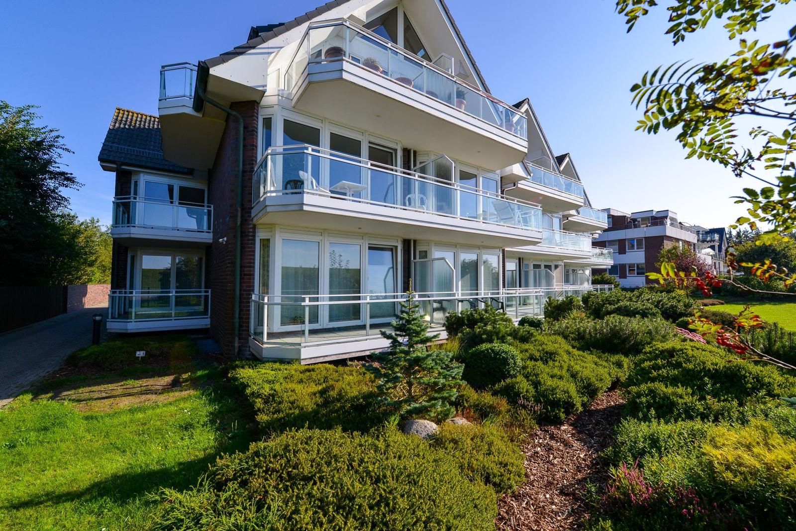 Moderne Ferienwohnung mit Balkonen und Garten. Sicht auf mehrere Etagen mit Glasgeländern.