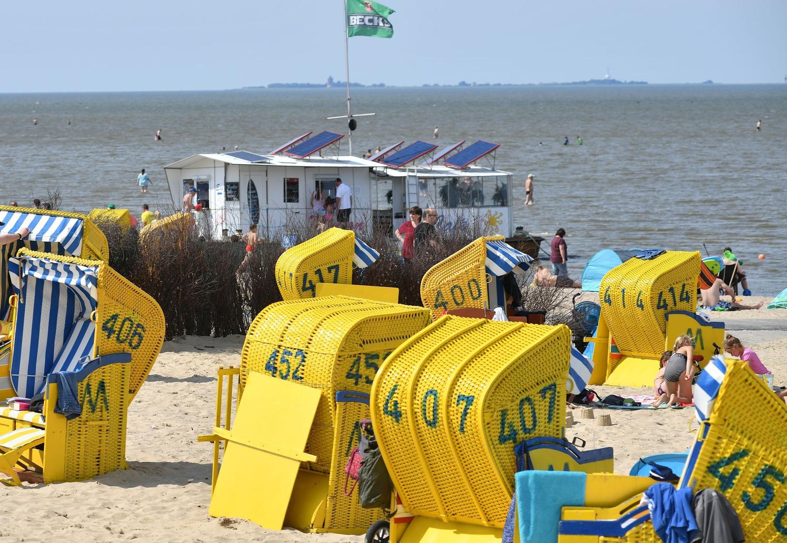 Strand mit gelben Liegestühlen und einem Strandhaus im Hintergrund.
