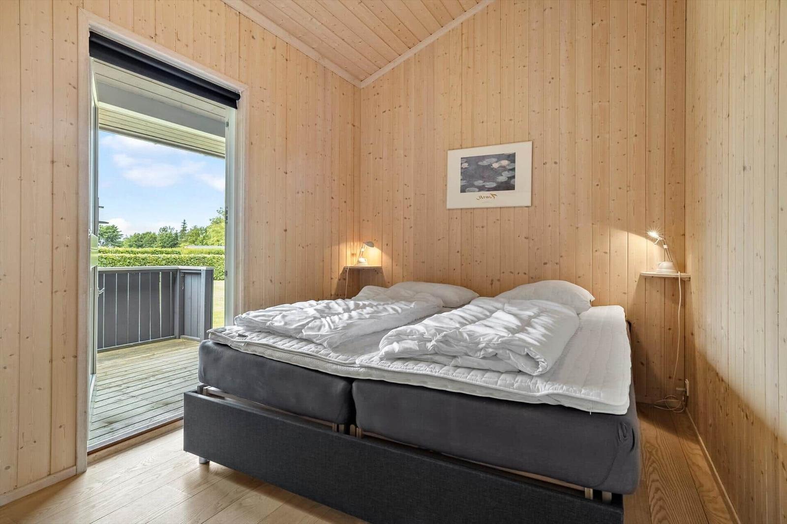 Bedroom with wooden walls, bed, and balcony door.